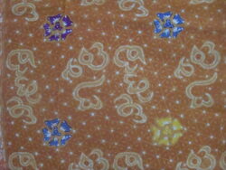 An orange-brown batik with blue, yellow and purple flowers.